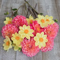 a bunch of pink and yellow flowers sitting on top of a wooden floor next to each other