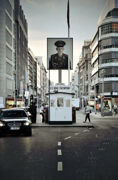 a man walking across a street next to tall buildings with billboards on the sides