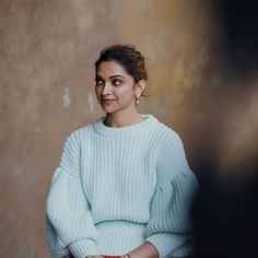 a woman in a white sweater and red skirt smiles at the camera with her arms crossed