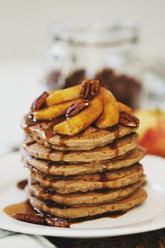 stack of pancakes topped with sliced bananas and pecans