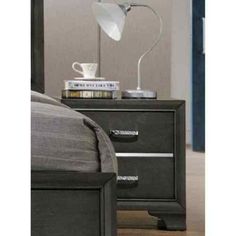 a nightstand with a lamp on top of it next to a bed