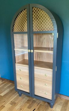 a wooden cabinet with glass doors on the front and bottom, against a blue wall