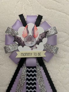 a purple ribbon with an image of a bat and the words mommy to be on it