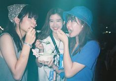 three girls are eating food together at a night club or bar, and one girl is wearing a blue shirt