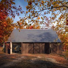 a barn in the fall with leaves on the ground and an old truck parked next to it