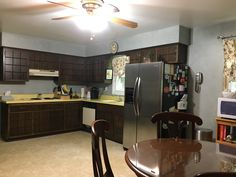 a kitchen with a refrigerator, stove and dining room table in the middle of it