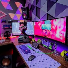 a desk with several computer monitors and keyboards on it in front of colorful wallpaper