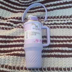 a pink water bottle sitting on top of a blanket