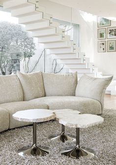 a living room filled with furniture and a spiral staircase in the background on top of a carpeted floor