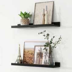 two black shelves with pictures and vases on them, one has a plant in it