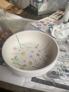 a white bowl sitting on top of a table covered in papers and other things next to it