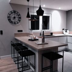 a kitchen with an island and bar stools in front of the counter top area