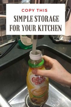 a hand holding a bottle of orange juice over a sink with the words copy this simple storage for your kitchen