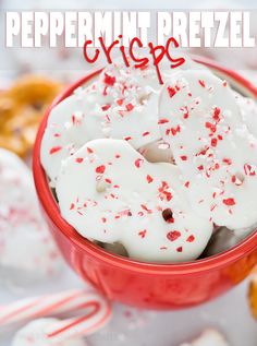 a red bowl filled with white frosted peppermint pretzels and sprinkles