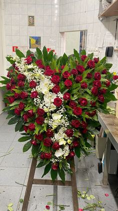 a large bouquet of red and white flowers on a table in a room with tile flooring