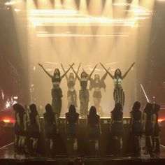 a group of women standing on top of a stage with their arms in the air