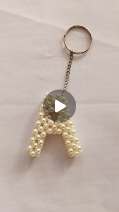 a keychain made out of pearls with a letter on the front and bottom