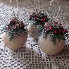 three white vases with red berries and pine cones