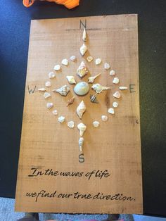 a wooden sign with shells on it that says in the news of life, we find out true direction