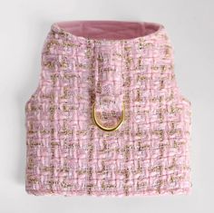 a pink and gold purse with a ring on the front, sitting on a white surface