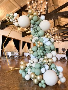 a very tall christmas tree made out of balloons and other decorations in a room with wooden floors