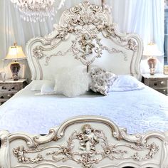 an ornate white bed with chandelier and pillows