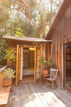 a wooden deck with chairs and potted plants on the side of it next to a building