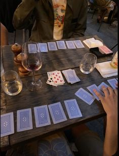 people sitting at a table with playing cards and wine glasses on top of the table