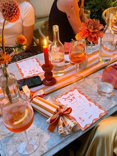 the table is set with orange and white striped napkins, wine glasses, candles, and flowers