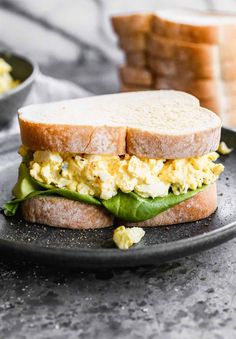 an egg and avocado sandwich is on a plate next to some toasted bread