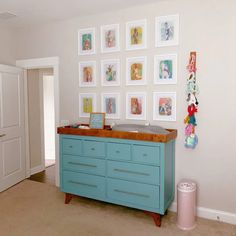 a baby crib in the corner of a room with many pictures on the wall