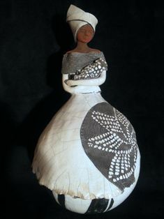 a black and white vase with an african design on the top, sitting in front of a dark background