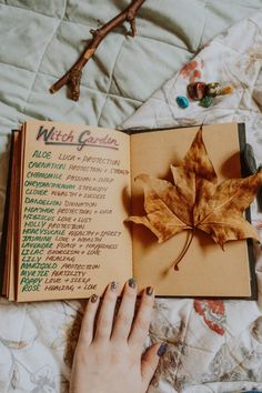 a person's hand is holding an open book with writing on it and a maple leaf