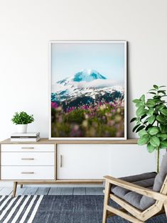 a living room with a chair, plant and large poster hanging on the wall above it