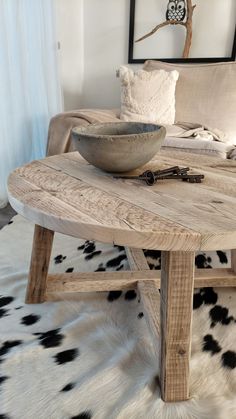 a wooden table sitting on top of a white cowhide rug next to a couch