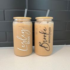 two mason jars filled with iced coffee sit next to each other on a counter top