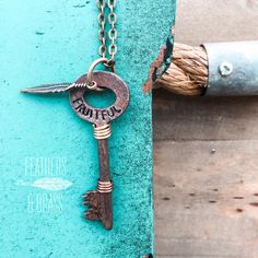 an old key is attached to a chain with a feather charm hanging from it's end