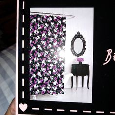 a black and pink bathroom with skulls on the shower curtain next to a vanity table