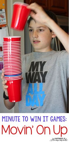 a young boy holding up a stack of red cups with the words, minute to win it games movin'on up