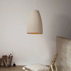 a room with a bed, chair and lamp hanging from the ceiling