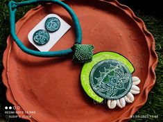 a green and white necklace sitting on top of a red plate