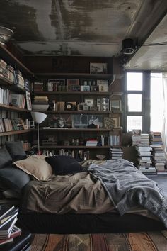 a bedroom with lots of books on shelves and a bed in the middle of it