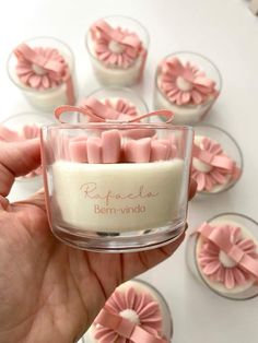 a hand holding a small glass container filled with pink candles