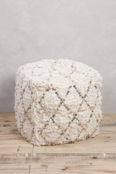 a white poufce sitting on top of a wooden floor next to a wall