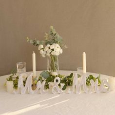 the table is set with candles, flowers and mr and mrs signs on it's centerpiece