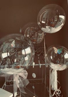 three clear balloons with bows and butterflies on them