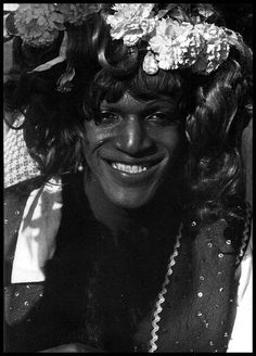 a black and white photo of a woman with flowers in her hair smiling at the camera