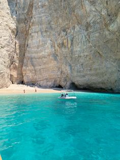 a boat in the water near a rocky cliff