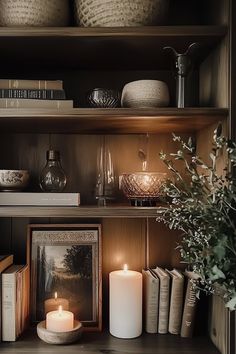 a shelf with books and candles on it