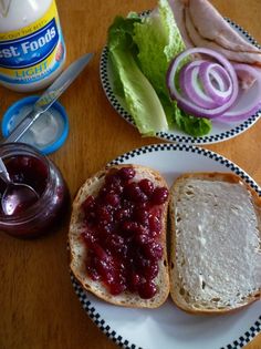 two plates with sandwiches and jam on them sitting on a table next to a jar of jelly